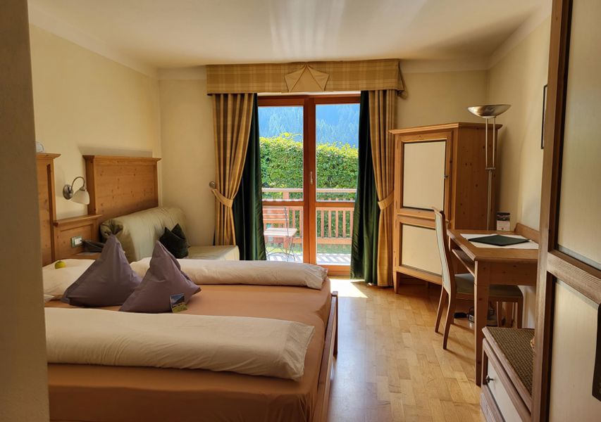 Camera soleggiata con letto matrimoniale, divano letto, pavimento in legno e balcone a sud